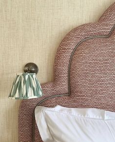 a lamp on the side of a bed next to a red and white headboard