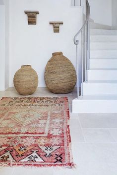 two vases sitting on top of a rug next to a stair case