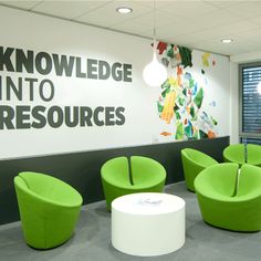 an office with green chairs and a large sign on the wall that says knowledge into resources