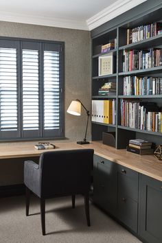 a home office with bookcases, desk and chair in front of the window