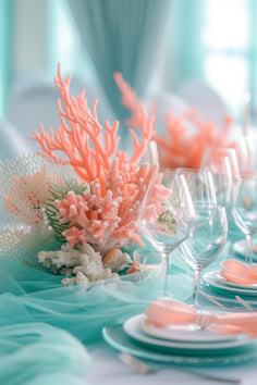 the table is set with corals and wine glasses