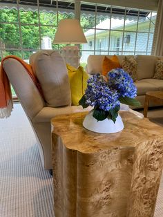 a living room filled with furniture and a vase on top of a wooden table in front of a window