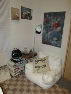 a white chair sitting in a living room next to a lamp and pictures on the wall