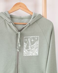 Navigate through life's storms with elegance and assurance in our "This Too Shall Pass" sleeve affirmation zip hoodie. Crafted from premium ring-spun cotton, this hoodie offers superb comfort and durability. Featuring a sophisticated linocut design of a boat braving a storm on the front, this piece symbolizes resilience and the transient nature of challenges. The timeless mantra "This Too Shall Pass" is elegantly scripted along the sleeve, serving as a gentle reminder that no matter the severity Linocut Design, Affirmation Jewelry, Mental Health Recovery, This Too Shall Pass, Stormy Sea, Happy Vibes, A Storm, Zip Up Hoodie, Front Design