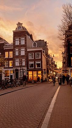 people are walking down the street in front of some buildings and bicycles on the sidewalk