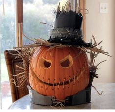 a decorated pumpkin sitting on top of a table next to a basket filled with hay