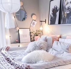 a white bed topped with lots of pillows next to two pictures on the wall above it