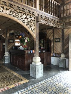 an ornately decorated lobby with wooden walls and columns, carpeted flooring and rugs