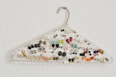 a white lace hanger with lots of different colored beads and charms hanging from it's side