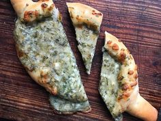 two pieces of pizza sitting on top of a wooden cutting board next to each other