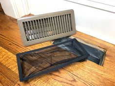 a metal vent sitting on top of a wooden floor