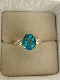 a ring with a blue stone and three white stones in it on top of a box