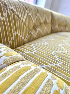 a close up view of a yellow and white patterned couch with buttons on the back