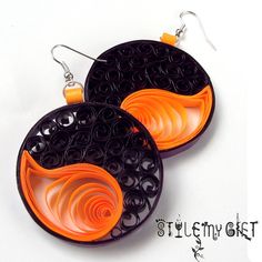 two black and orange earrings with swirls on them, one is hanging from the side