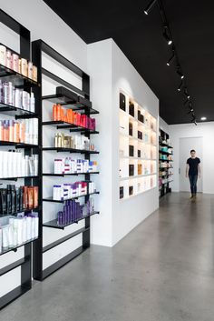 a man is walking through a store with shelves full of hair care products on the wall