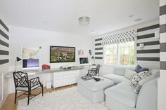 a living room with black and white stripes on the walls, couches, desk and television