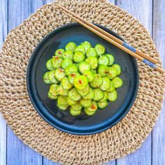 a black plate topped with brussel sprouts next to chopsticks