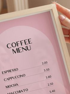 a person holding up a menu in front of a pink background with the words coffee menu on it