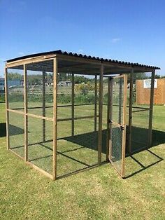 a chicken coop in the middle of a field with grass and blue sky behind it