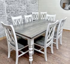 a dining room table with six chairs in front of a brick wall and wooden floor