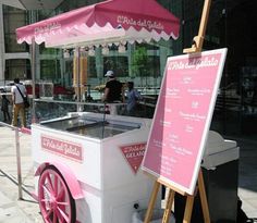 a pink and white cart sitting on the side of a street