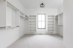 an empty room with white walls and open shelvings on either side of the window