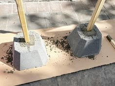 two cement blocks with wooden sticks sticking out of them on a piece of paper next to a sidewalk