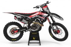 a red and black dirt bike on a stand with the words motocross written on it