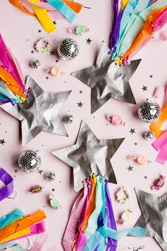 colorful streamers and confetti are scattered around the star shaped decorations on this pink background