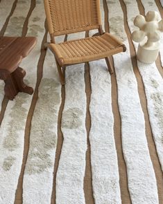 a chair sitting on top of a white rug next to a table and vases