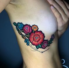 a close up of a woman's breast with flowers on it and writing underneath the breast