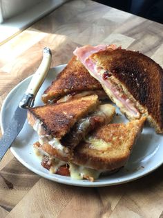 a sandwich cut in half sitting on top of a white plate next to a knife