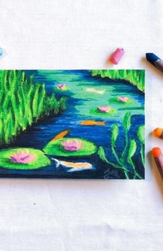 some colored crayons are next to a drawing of water lillies and lily pads