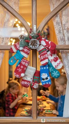 a christmas wreath with stockings hanging from it's side in front of a window