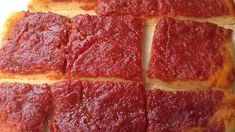 square slices of pizza sitting on top of a white plate covered in red toppings