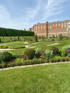 a large building sitting in the middle of a lush green field next to a garden