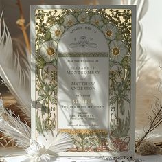 an ornate wedding card with flowers and leaves on the front is surrounded by white feathers