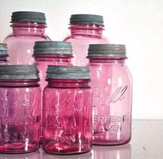 four pink mason jars are lined up on the table