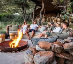 several people sitting around a fire pit on couches