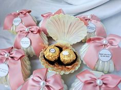 pink and white candies in shell shaped containers with bows around them on a table