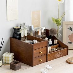 an open wooden drawer containing cosmetics and other personal care items on a table next to a vase with flowers in it