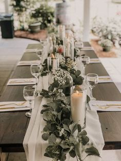 a long table is set with candles and greenery for an elegant dinner or party