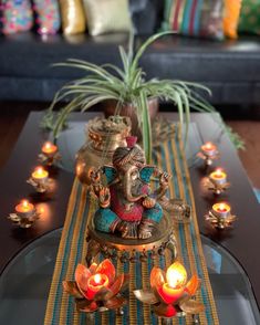 an elephant figurine sitting on top of a glass table with candles around it