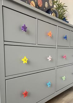 a gray dresser with colorful stars on the drawers and drawer knobs attached to it