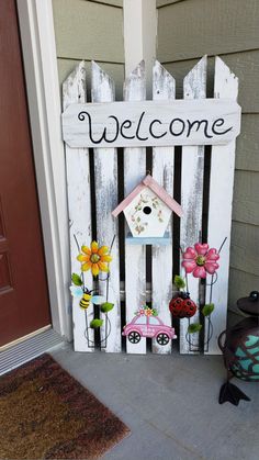 a welcome sign with flowers and a birdhouse