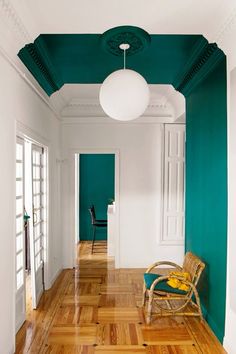 an empty room with green walls and wood flooring in the center, along with a wicker chair