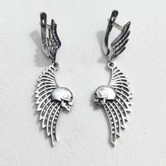 Skull and Wing Earrings Add a touch of edge to your style with these Skull and Wing Earrings. Crafted from solid sterling silver, these earrings feature an intricately detailed skull paired with an elegant wing design, weighing approximately 4.7 grams. They are perfect for those who appreciate unique, handcrafted jewelry with a gothic flair. ◆ Features: SKU: 41024 Brand new sterling silver 925 ring. Not plated!, 100% solid silver metal! Approx. weight of the product - 4.7g. Manufacturing and cou Winged Sterling Silver Earrings In Silver, Silver Winged Sterling Silver Earrings, Silver Sterling Silver Winged Earrings, Winged Sterling Silver Earrings As Gift, Winged Sterling Silver Earrings For Gift, Sterling Silver Winged Earrings Gift, Elegant Winged Metal Jewelry, Elegant Silver Winged Earrings, Gothic Sterling Silver Skull Earrings