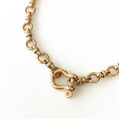 a close up of a gold necklace on a white surface with an oval link around it