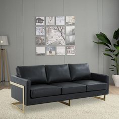 a black leather couch sitting on top of a white rug in front of a gray wall