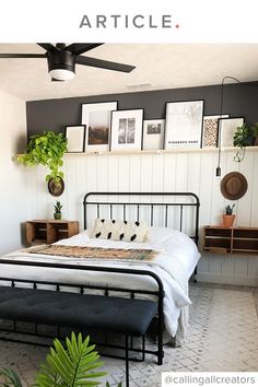 a bedroom with a bed, plant and pictures on the wall above it's headboard